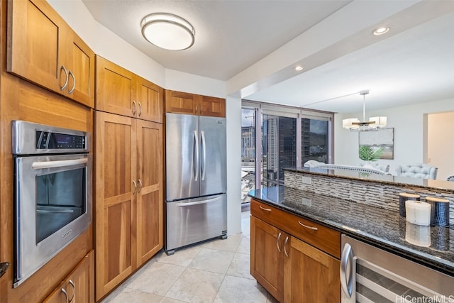 kitchen with stainless steel appliances, decorative light fixtures, beverage cooler, dark stone countertops, and a chandelier