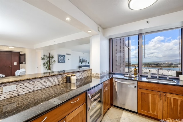 kitchen featuring sink, dishwasher, a wealth of natural light, beverage cooler, and dark stone countertops