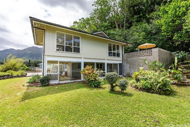 rear view of house featuring a yard, a mountain view, and a sunroom