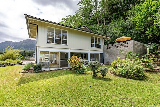 rear view of property featuring a lawn and a mountain view