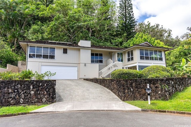 view of front of property with a chimney, driveway, stairs, and a garage
