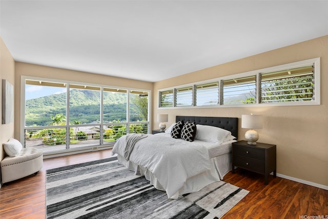 bedroom with wood finished floors, baseboards, and multiple windows