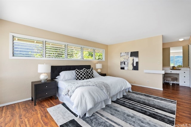 bedroom with multiple windows, built in desk, and dark hardwood / wood-style flooring