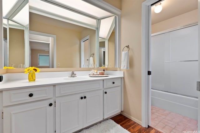 full bathroom featuring combined bath / shower with glass door, wood finished floors, vanity, and baseboards