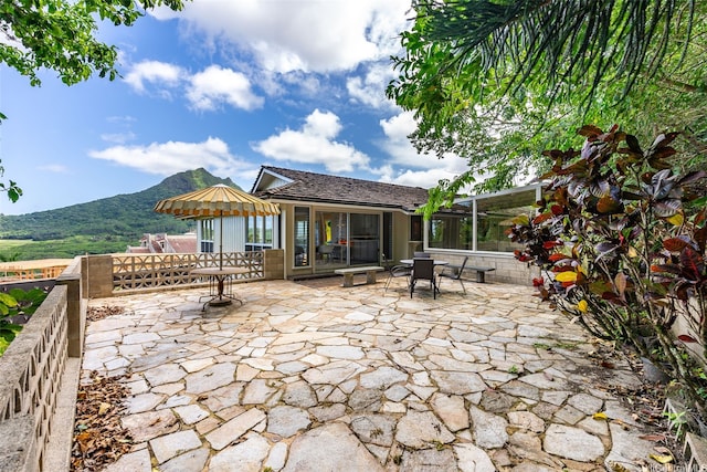 view of patio / terrace with outdoor dining space, glass enclosure, and a mountain view