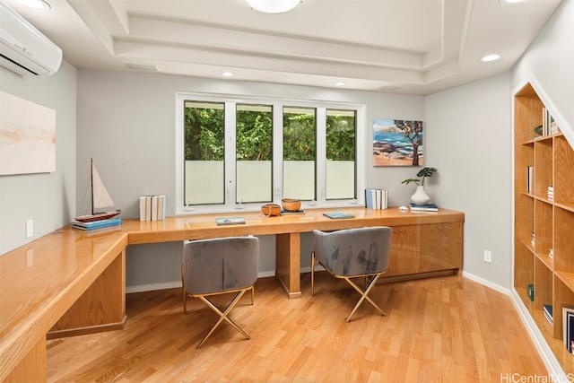 office featuring light hardwood / wood-style floors, a wall unit AC, built in desk, and a raised ceiling