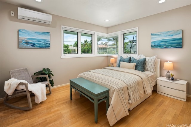 bedroom featuring a wall mounted AC, light hardwood / wood-style flooring, and multiple windows