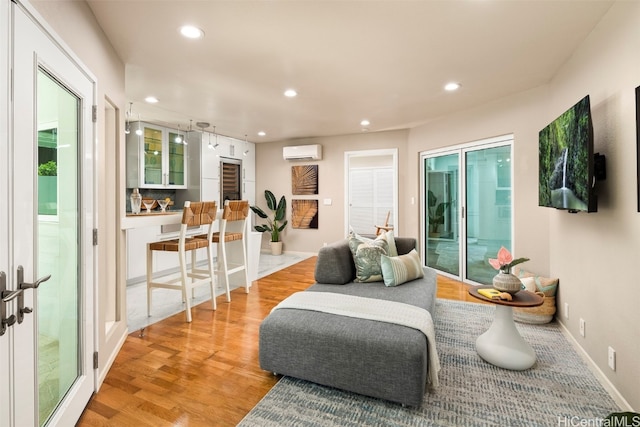 sitting room featuring a wall mounted air conditioner and light wood-type flooring