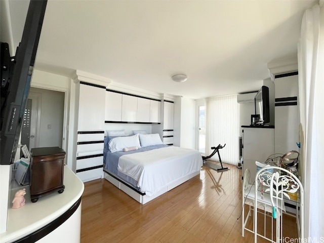 bedroom featuring a wall unit AC and light hardwood / wood-style floors