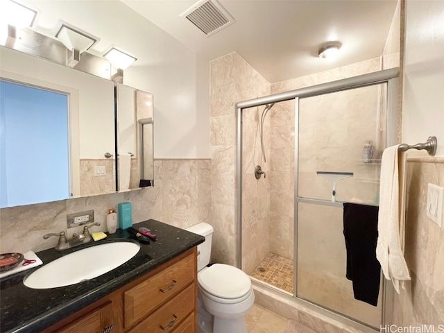 bathroom featuring toilet, tile patterned flooring, vanity, tile walls, and an enclosed shower