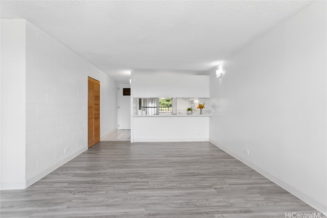 unfurnished living room featuring a textured ceiling and light hardwood / wood-style floors