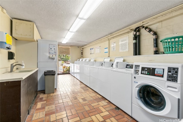 laundry room featuring washer and dryer, a textured ceiling, and sink