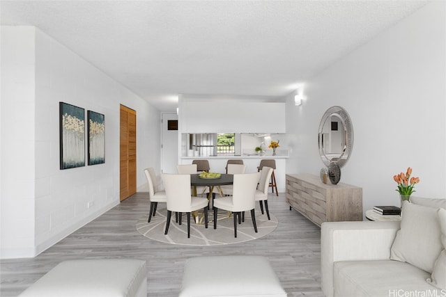 dining area with light hardwood / wood-style floors and a textured ceiling