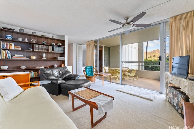 living room with a textured ceiling, light colored carpet, and ceiling fan