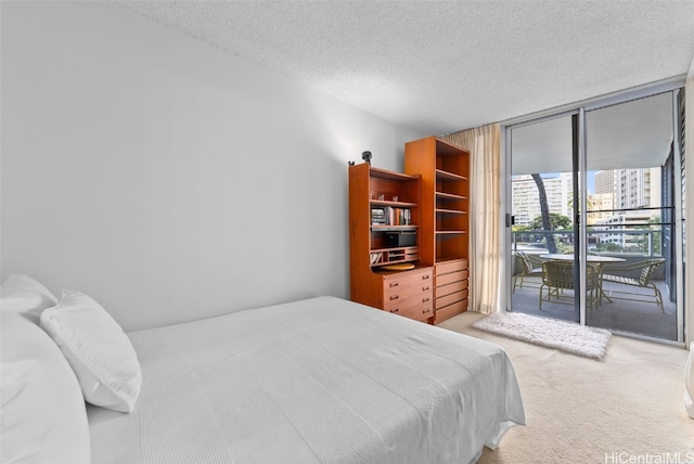 carpeted bedroom with access to outside, a textured ceiling, and floor to ceiling windows