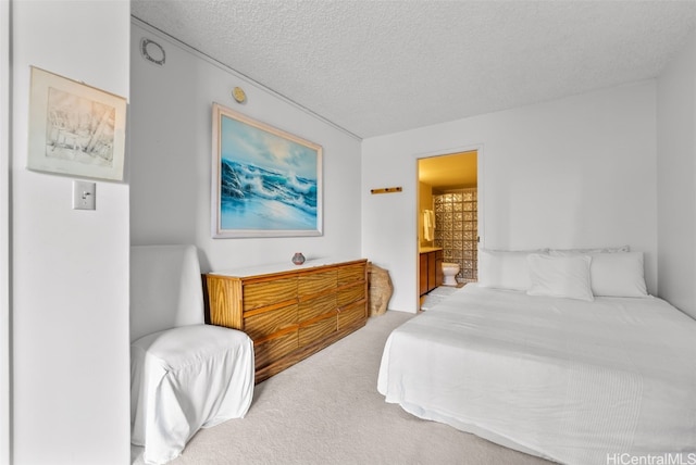 carpeted bedroom featuring a textured ceiling and connected bathroom