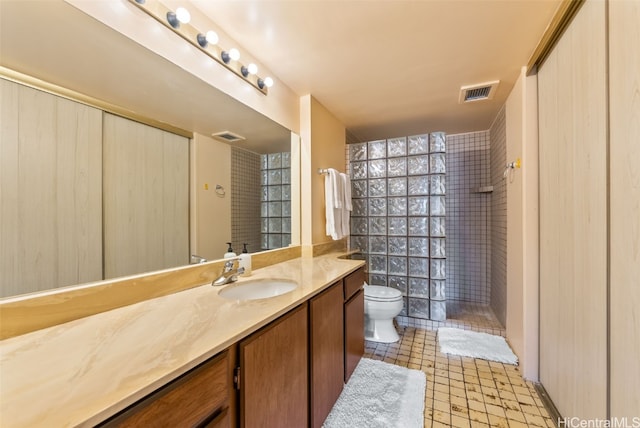 bathroom featuring toilet, vanity, and tiled shower