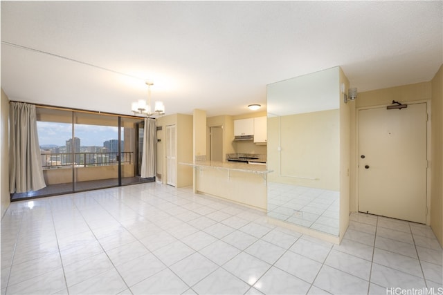 unfurnished room with a notable chandelier, light tile patterned floors, and floor to ceiling windows