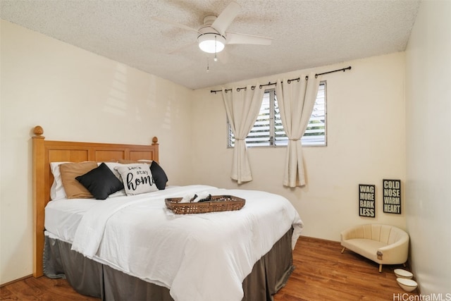 bedroom with a textured ceiling, hardwood / wood-style flooring, and ceiling fan