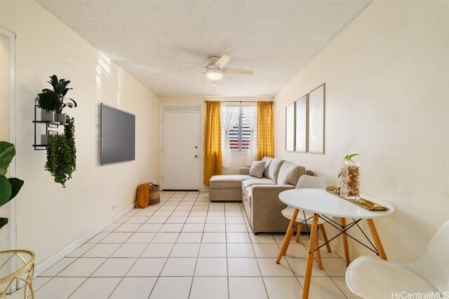 living room with a textured ceiling, ceiling fan, and light tile patterned flooring