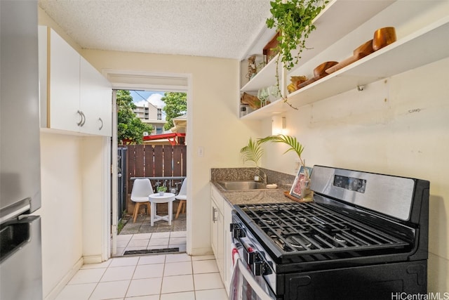 kitchen featuring sink, light tile patterned floors, a textured ceiling, appliances with stainless steel finishes, and white cabinetry