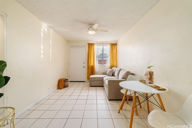 living room featuring ceiling fan, light tile patterned flooring, and a textured ceiling