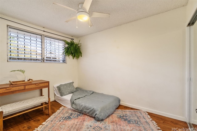 sitting room with ceiling fan, dark wood-type flooring, and a textured ceiling