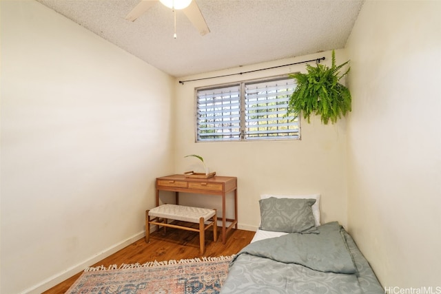 living area featuring vaulted ceiling, ceiling fan, wood-type flooring, and a textured ceiling