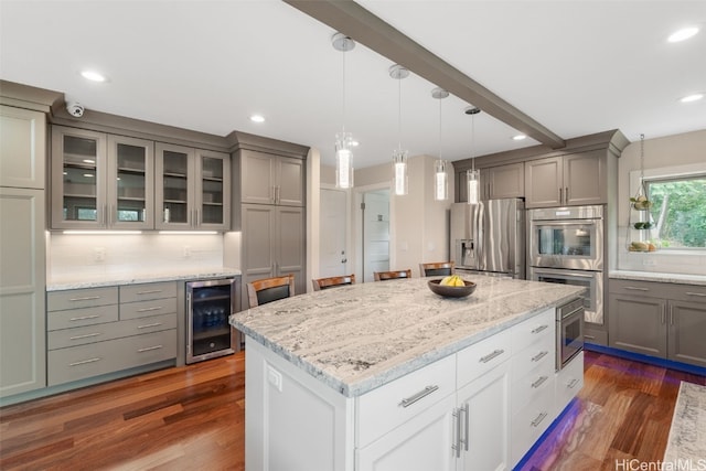 kitchen featuring beverage cooler, a kitchen island, backsplash, dark wood-type flooring, and stainless steel appliances