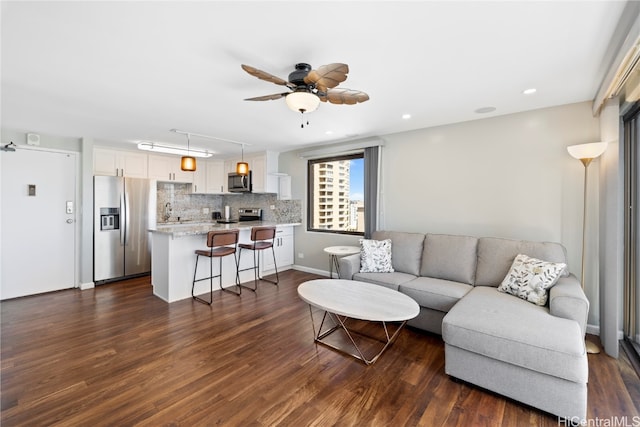 living room with sink, ceiling fan, and dark hardwood / wood-style flooring