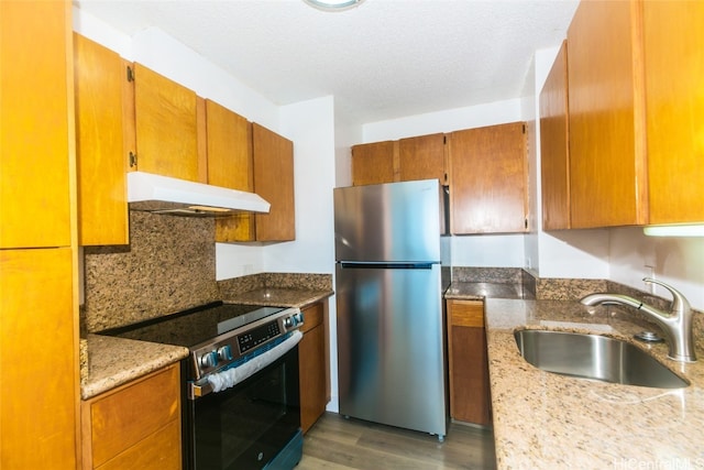 kitchen featuring dark wood-type flooring, sink, light stone countertops, appliances with stainless steel finishes, and a textured ceiling