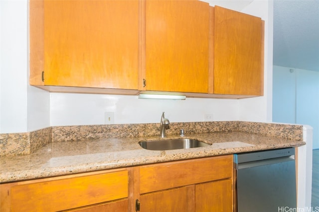 kitchen with dishwasher, light stone countertops, sink, and wood-type flooring