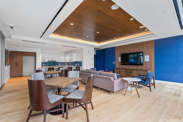 dining room featuring light hardwood / wood-style floors, a raised ceiling, and wooden ceiling