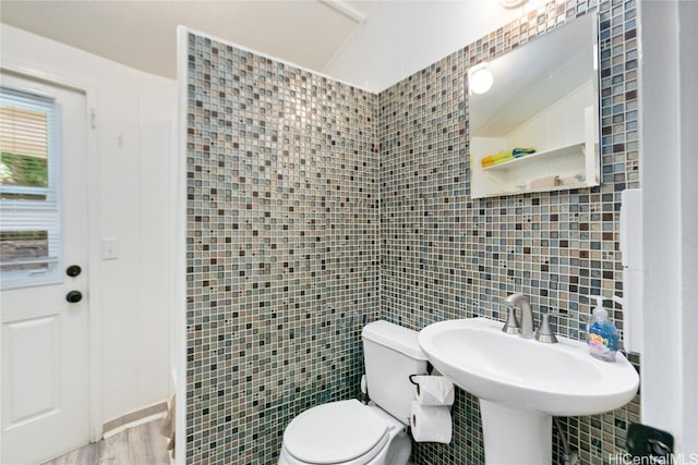 bathroom featuring lofted ceiling, hardwood / wood-style floors, tile walls, toilet, and sink