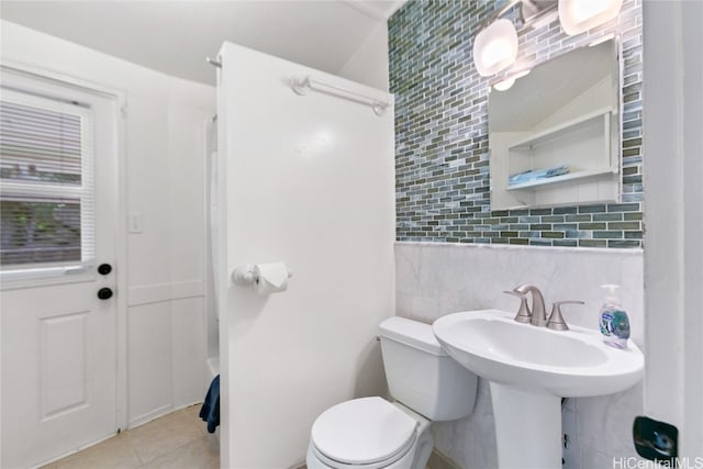 bathroom with toilet, decorative backsplash, tile patterned floors, and tile walls
