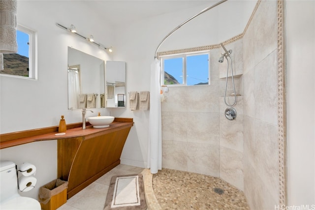 bathroom with a tile shower, a healthy amount of sunlight, tile patterned flooring, and vanity