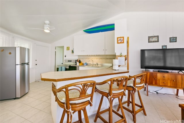 kitchen featuring lofted ceiling, kitchen peninsula, stainless steel appliances, white cabinets, and ceiling fan