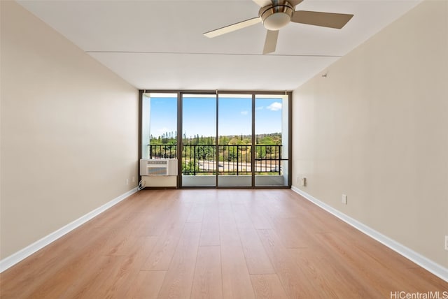 unfurnished room featuring cooling unit, expansive windows, light wood-type flooring, and ceiling fan