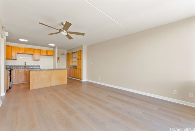 kitchen with light wood-type flooring, stainless steel range oven, a center island, ceiling fan, and light stone counters