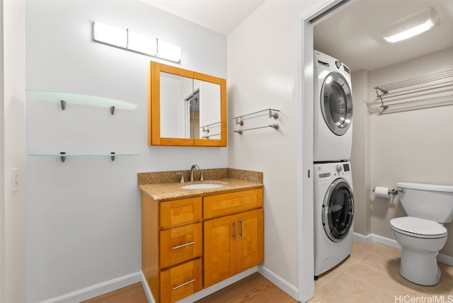 interior space with vanity, stacked washer / dryer, tile patterned floors, and toilet