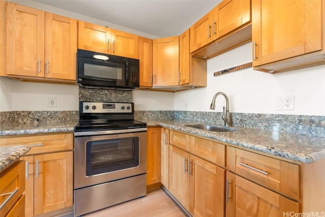 kitchen featuring stainless steel electric range, sink, light stone counters, and light wood-type flooring