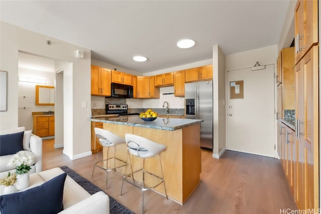 kitchen with wood-type flooring, a kitchen bar, a kitchen island, electric range, and stainless steel refrigerator with ice dispenser