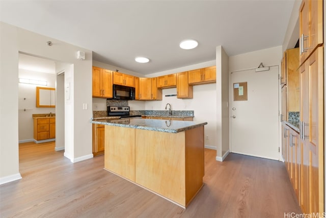 kitchen with dark stone counters, sink, a center island, stainless steel range with electric cooktop, and light hardwood / wood-style floors