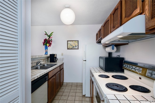 kitchen with white appliances, light tile patterned flooring, sink, tile counters, and exhaust hood