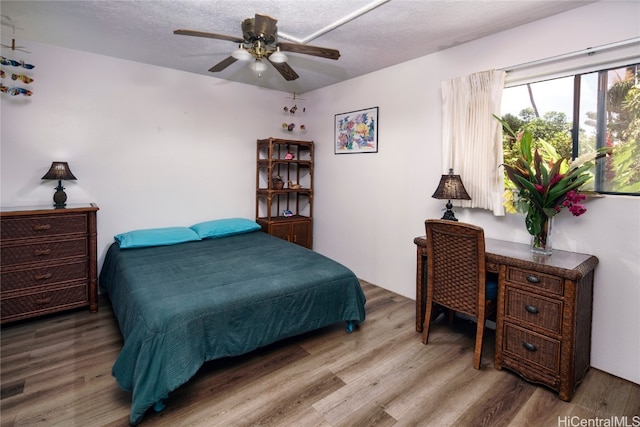 bedroom featuring a textured ceiling, wood-type flooring, and ceiling fan