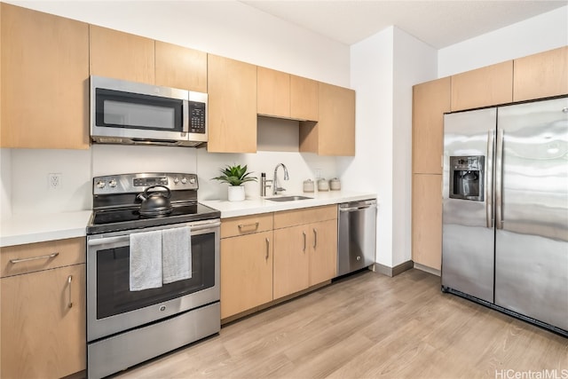 kitchen featuring sink, stainless steel appliances, light hardwood / wood-style flooring, and light brown cabinets