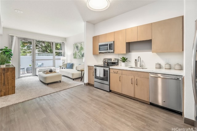 kitchen featuring light brown cabinetry, sink, stainless steel appliances, and light hardwood / wood-style floors