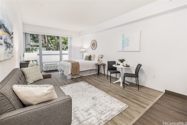 bedroom with hardwood / wood-style floors and a wall mounted AC