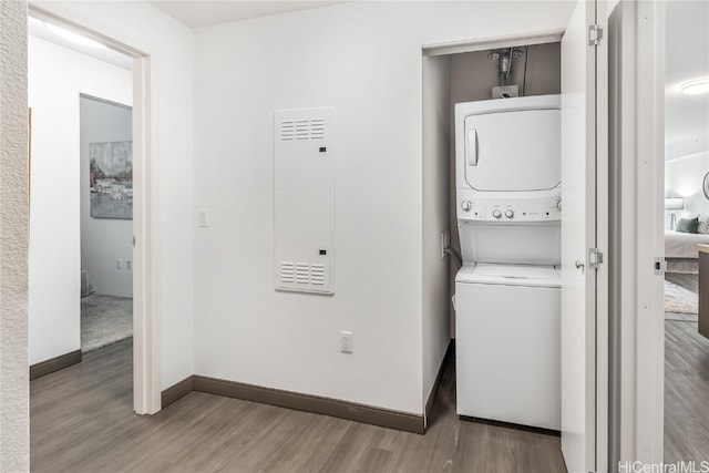 clothes washing area with hardwood / wood-style floors and stacked washer and dryer