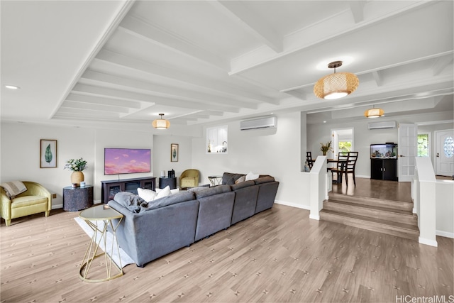 living room with a wall mounted air conditioner, light wood-type flooring, and beamed ceiling